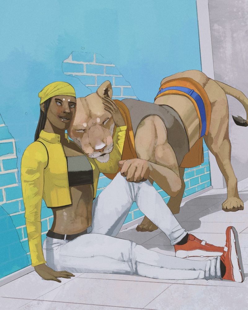 A woman in a yellow jacket and white jeans cuddling a large lioness while she sits on the ground against a wall.
