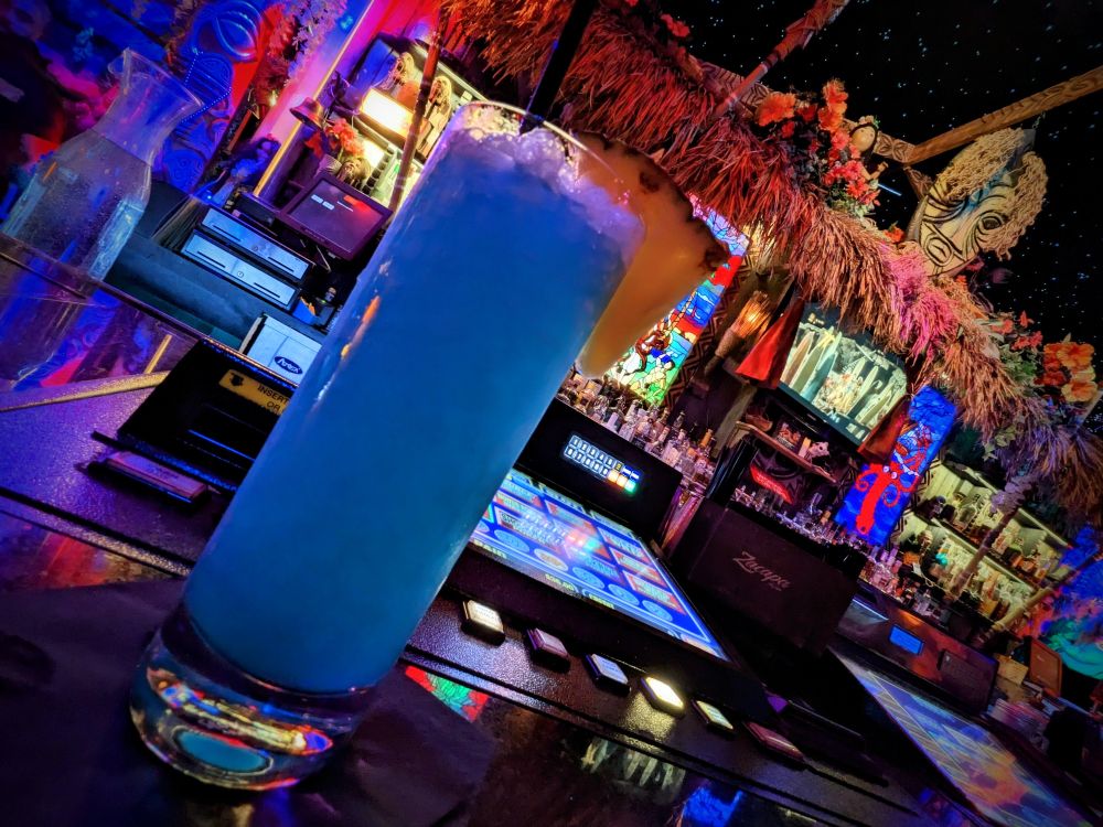 A blue drink at a Las Vegas tiki bar with a wedge of pineapple on the glass rim. 