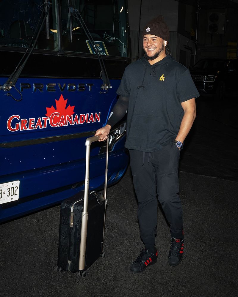 Seattle Mariners pitcher Luis Castillo in front of a bus that says Great Canadian across the front.