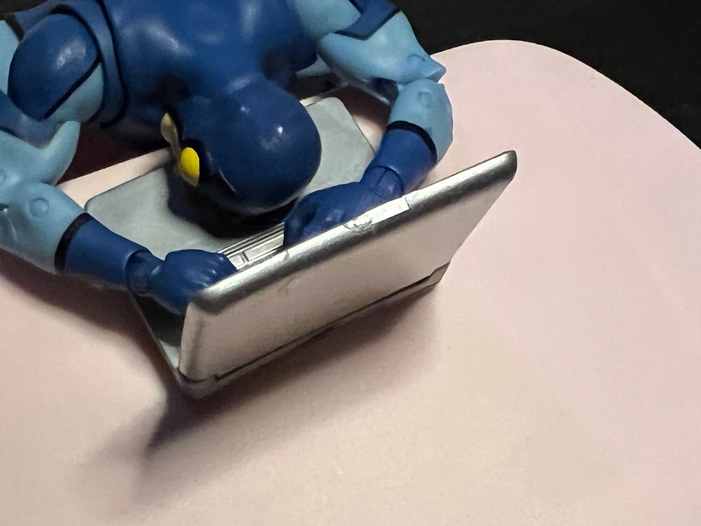 Ted Kord action figure asleep as computer