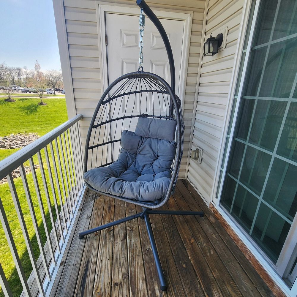 Grey egg shaped hanging chair with a cushion on an apartment balcony