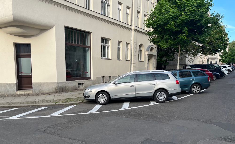 Ein Auto parkt auf einer markierten Sperrfläche im Kurvenbereich. 