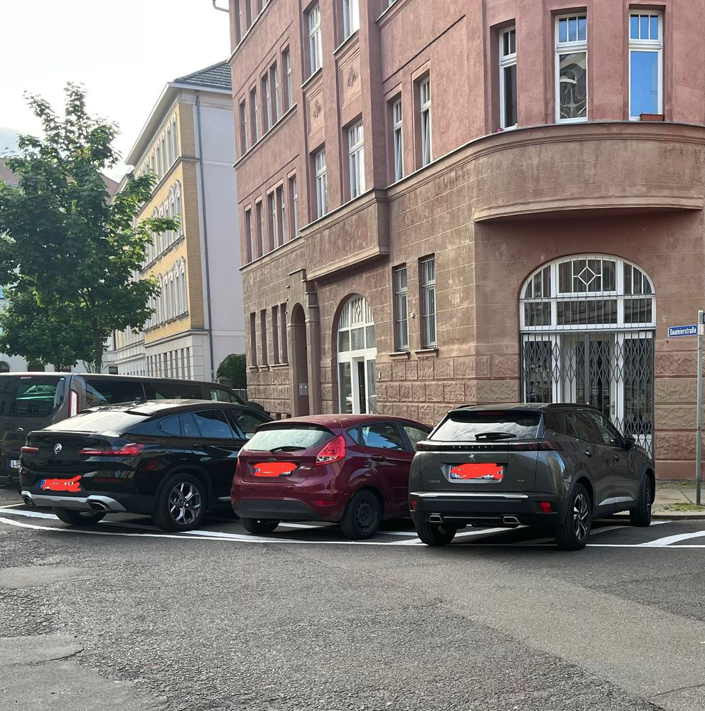 Mehrere Autos parken auf einer markierten Sperrfläche im Kurvenbereich