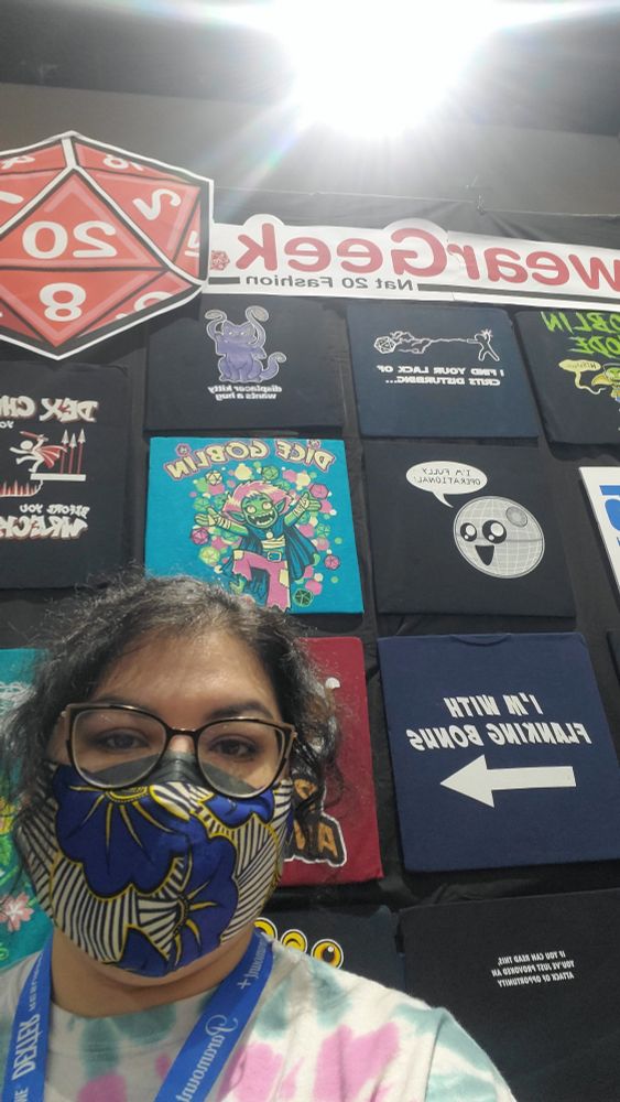 Amanda, masked up, in front of the WereGeek t-shirt booth.