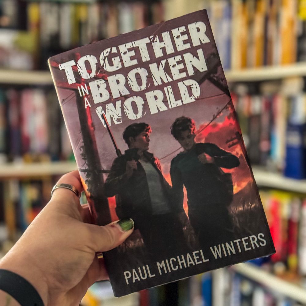 The cover of Together in a Broken World by Paul Michael Winters. 

Book description: 

Two boys fall in love in a deadly world, but it's the secrets they keep that might kill them.

Seventeen-year-old Zach was visiting his uncle in a small Montana town when a mysterious illness ripped through the world. Most died, but those who survived the Infection became mindless killers, spreading the disease with a single scratch. Now, a year later, civilization lies in ruins, and Zach is the town's sole survivor. Desperately lonely, he longs to return to his family in Seattle, but his fears hold him captive.

Eighteen-year-old Aiden is on a critical mission for the covert Scientific Collective, delivering vials whose contents could cure the Infection. Tortured by his boyfriend's death, he welcomes the risks of the perilous journey. When a militia attacks Aiden, he flees to Zach's town.

The boys escape together and soon form a bond as they comfort each other in this desolate and broken world. The farther they travel, the more their affection grows, as do the forces pulling them apart. But their greatest threats are the secrets they keep. Zach hides details of his uncle's death, and Aiden conceals the vials' sinister origins. In order to survive, they'll have to confront the truths that could tear their love apart.