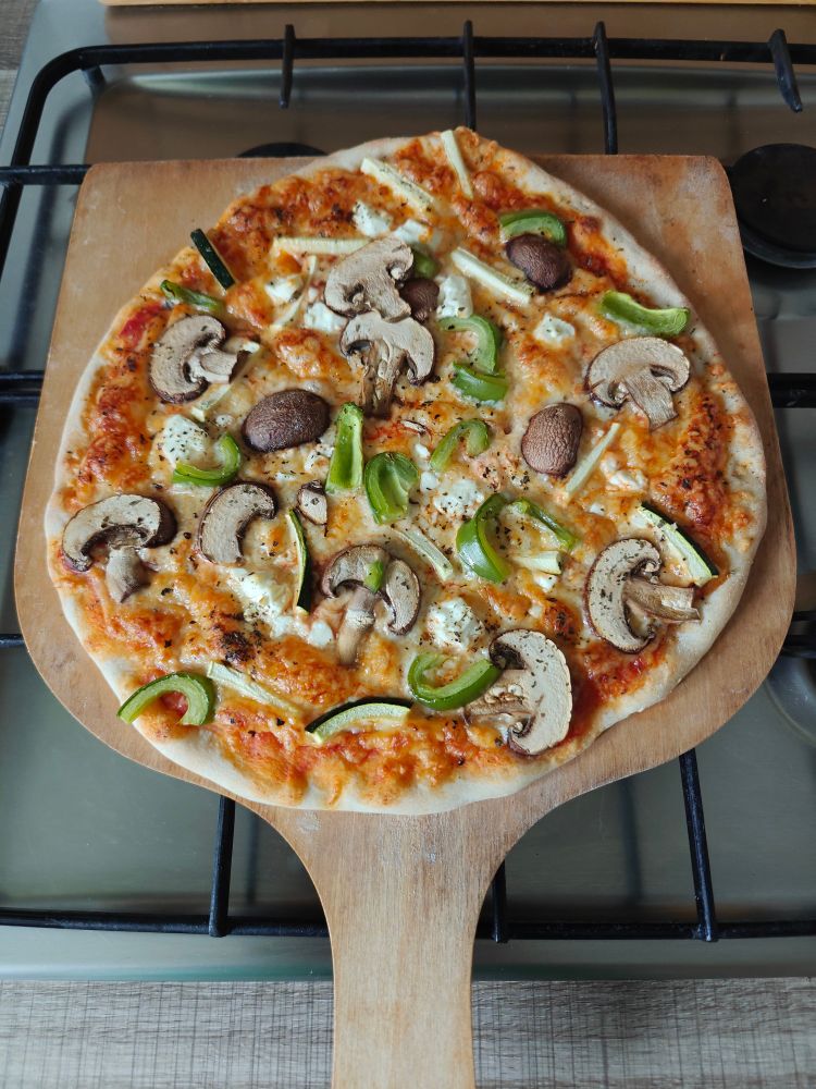 Hefeteig Fladen mit Tomatensabsche, geriebenem Käse und Gemüse auf Holzbrett 