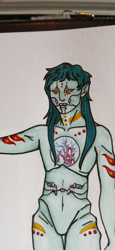 A colored illustration depicts a pale, minty skinned person standing straight, with one arm elevated. He looks to the viewer, eyes a bright yellow. Various markings in burgundy and yellow dot their body, creating lines and small circles. Choppily cut dark teal hair falls over her shoulders, with short bangs hanging over their forehead. Notably, fangs portude from their cheeks, and grow from their abdomen, attached to flush flaps of skin.