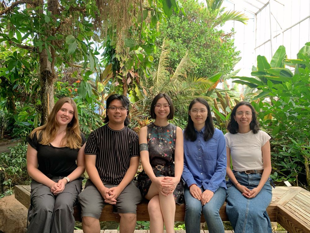 Group photo in the conservatory, we are all setting on a wooden bench with plants in the background. Left to right is Emma, Sam, Minya, Yudi, Angelique