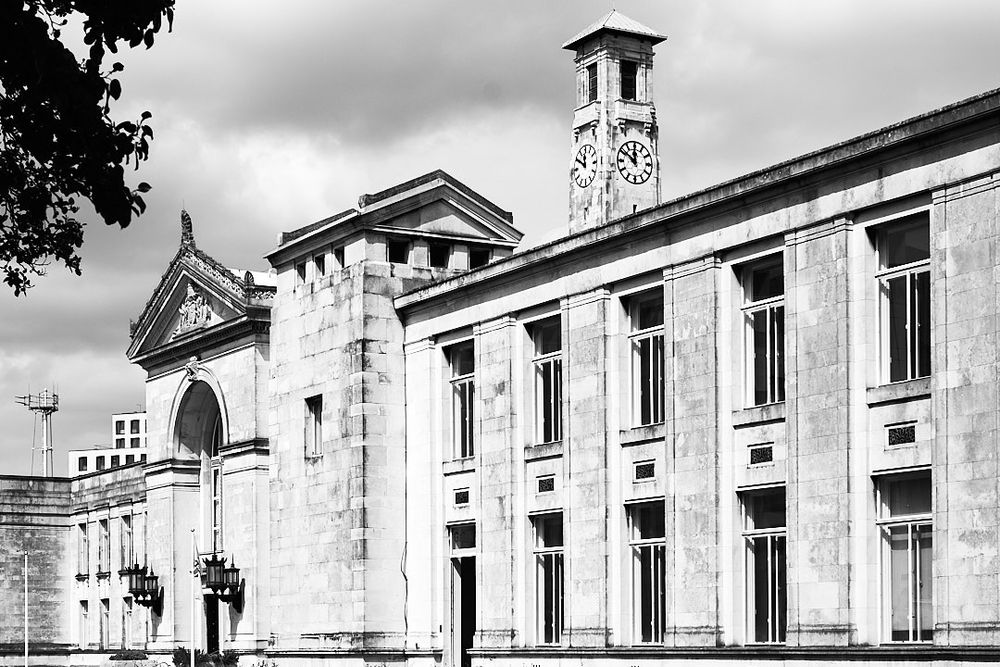 Black and white photo of Southampton Guildhall’s southern facade, with the clock tower peering over the roof. 
