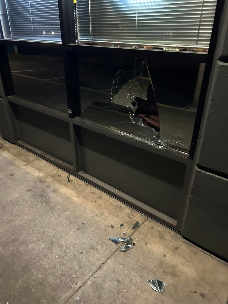 Image shows a set large 6-pane window. The center right pane has a large break in the center, as if hit with a bat or punched. 