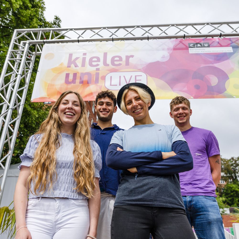 Eine Gruppe von Menschen steht unter einem Schild.