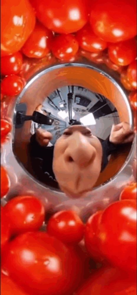 a reflection of a person 's face in a bowl of tomatoes .