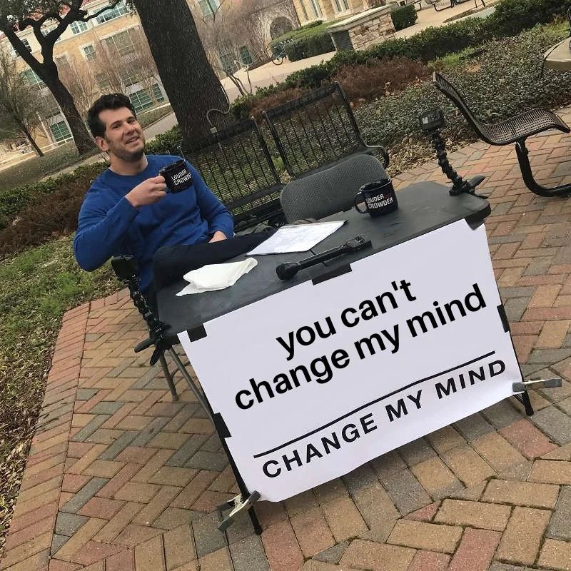 Meme of the man sitting at a table drinking coffee, with a large sign saying “change my mind” except here the space above that says “you can’t change my mind”
 