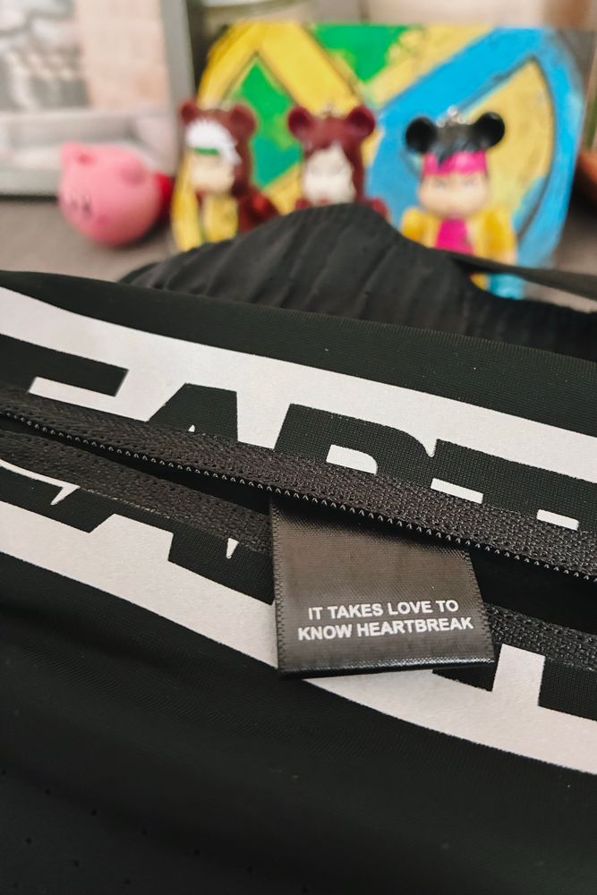 A close up of a running belt from a brand called Heartbreak with a tag reading “IT TAKES LOVE TO KNOW HEARTBREAK”