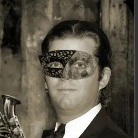 A puffy faced white guy, hair slicked back with hair gel, wearing a mask that is too small for his chinless face 