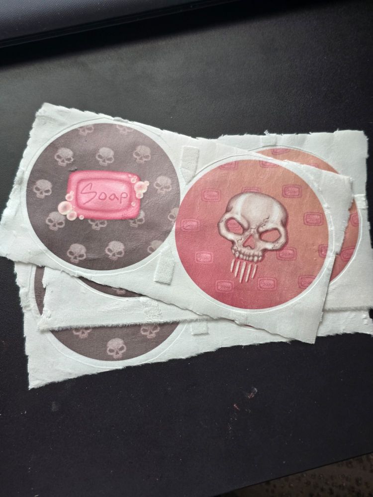 Ghoap sublimated and heat pressed keychains that still need to be sewn.
Soap bar and Ghost skull on opposite backgrounds.