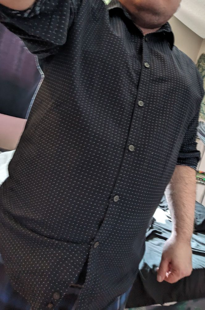 A photo of the same person in the same shirt as the previous photo, but the subtle curve of breasts is even smaller and less noticeable than previously. It even more looks like a fat cis man's chest rather than trans guy breasts.