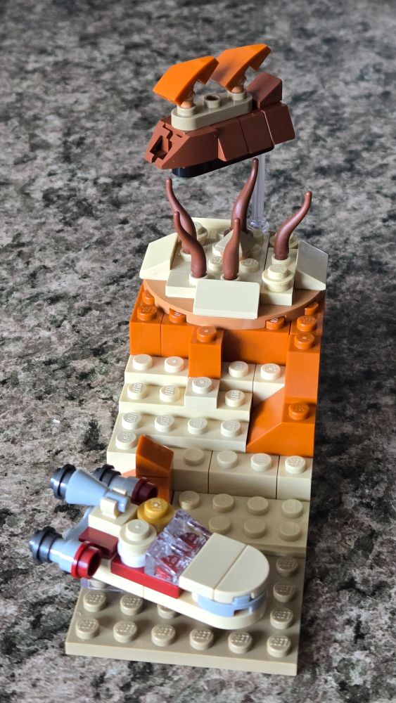 Micro lego build of the Star Wars planet Tatooine (Desert planet). Foreground displays Luke's Landspeeder, and the background contains Jabba's Sail Barge and the Sarlacc Pit