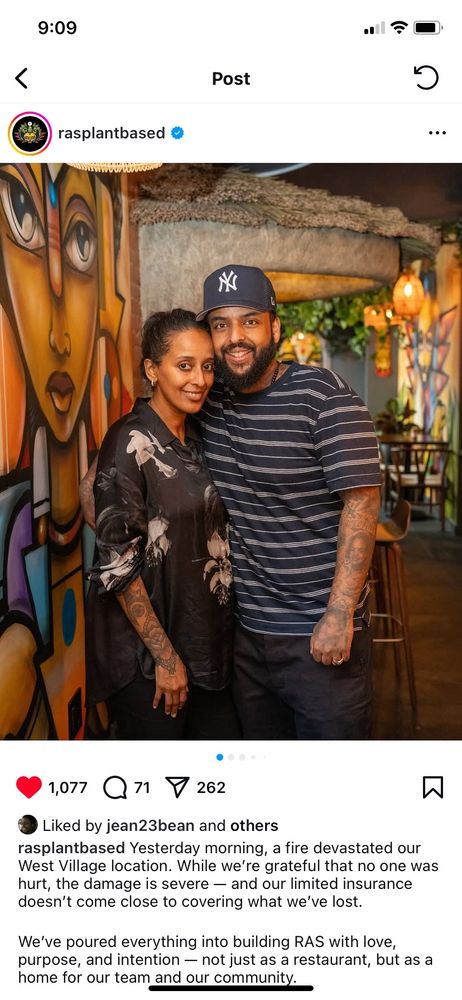 Instagram post by owners of Ras West Village with an image of them (Black woken in a black dress with white flowers and Black man in a striped polo shirt) posing for the camera in their restaurant with murals behind them. Words in post say they experienced a devastating fire that their insurance isn’t enough to cover and they are seeking donations.