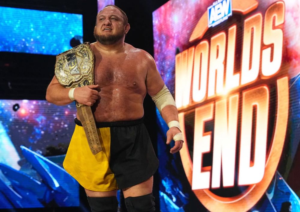 wrestler samoa joe holding a title belt, wearing black and yellow trunks