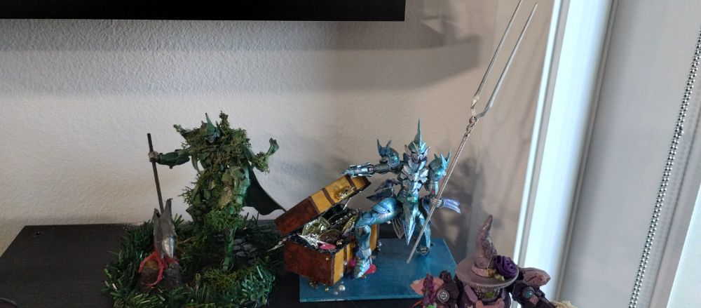 Picture of water worn knight Gundam diorama next to a green knight overgrown diorama. 
