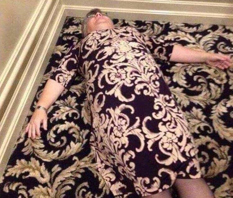 A woman lying on a carpet; her dress is a nearly perfect match for it.