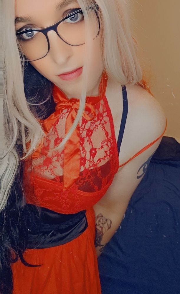 Stone faced platinum blonde in a sheer red dress with black accents