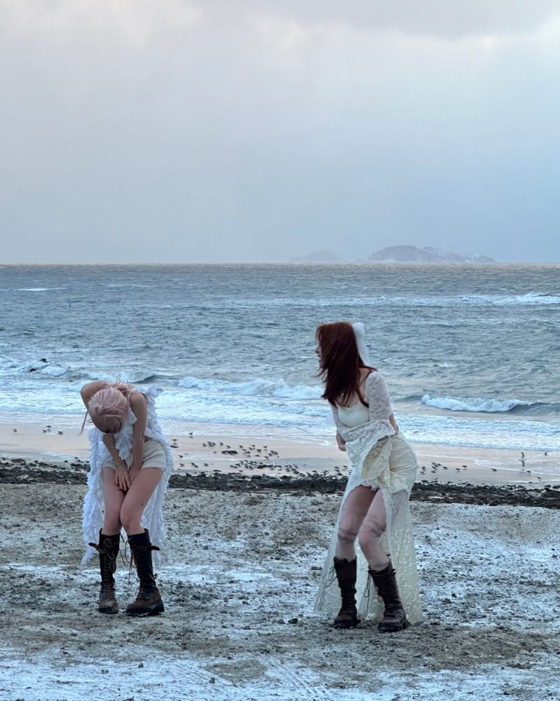 Purinz at the beach in white lace dresses and boots for Hot filming, acting out some kind of chaotic mating ritual in a photo you can hear yelling, from Chaewon's insta