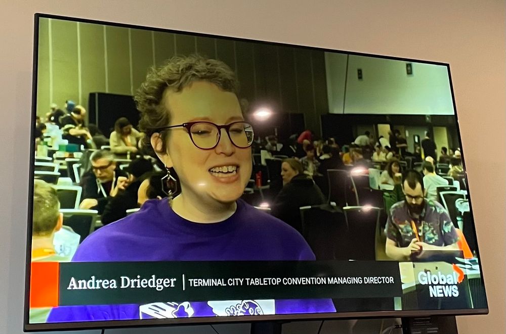 a photo of a tv screen showing Global News running a story on TCTC with a short haired women labelled as Andrea Driedger / managing director 