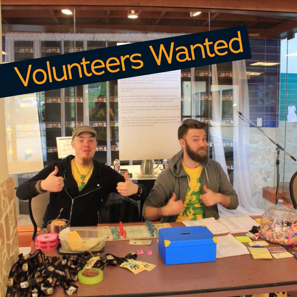 Two TCTC volunteers sit behind the registration desk. They give thumbs up. 