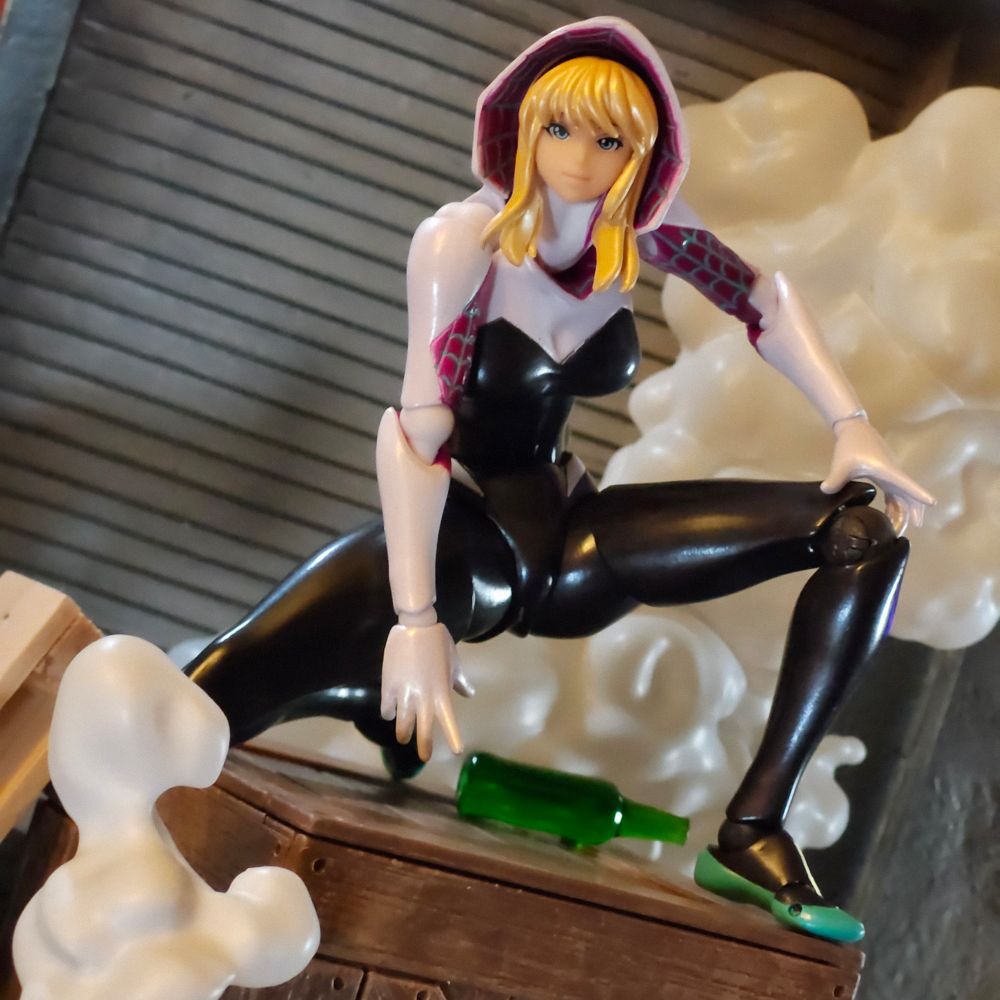 Toy photo: Revoltech Spider-Gwen sits in a crouching pose on top of all crate and surrounded by smoke