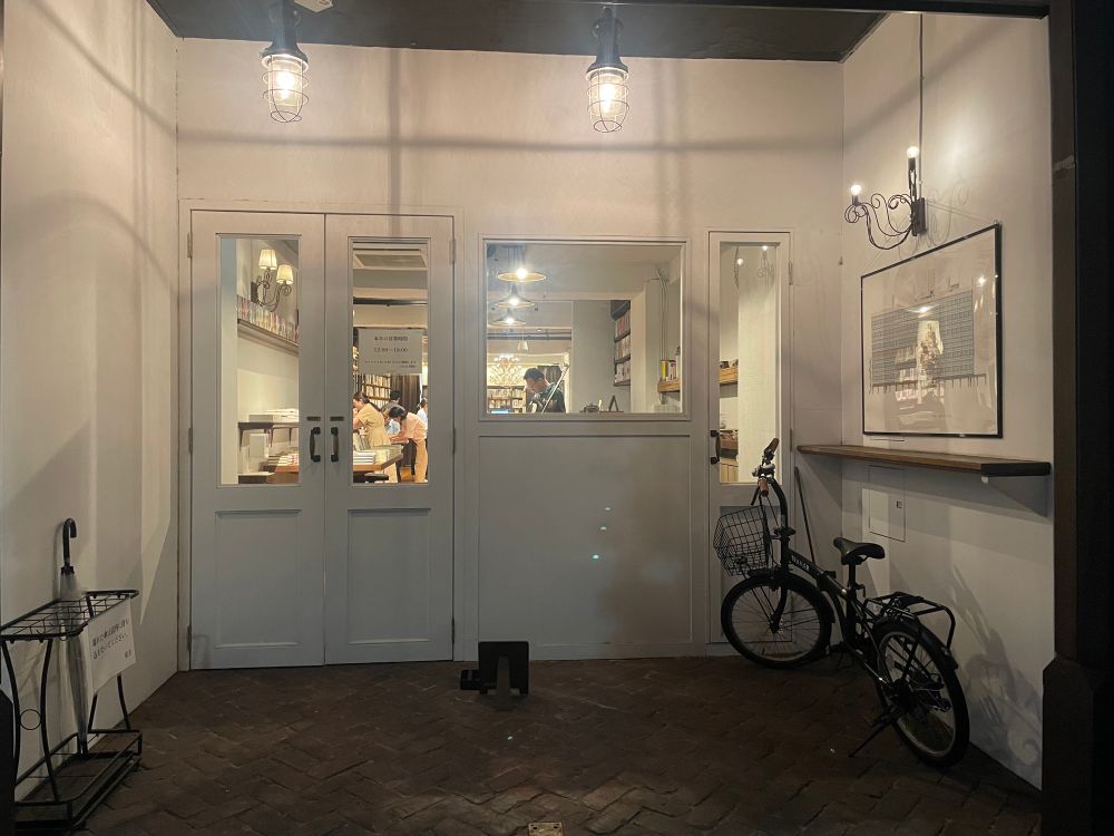 本屋UNITÉの入り口。白い壁とドアの奥に本棚が並んでいる