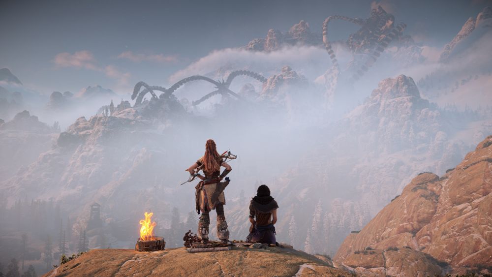 Aloy stands next to Odd Grata on a cliff overlooking the remains of a giant machine in Horizon Zero Dawn Remastered (2024).