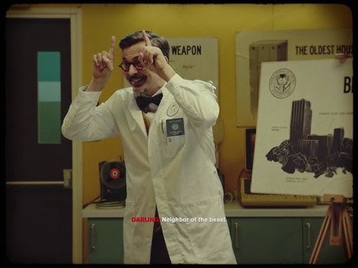 Dr. Casper Darling [Control (2019)] stands in a Federal Bureau of Control (FBC) lab, smiling & using his hands to make “Devil Horns” while describing the number 665 as, “Neighbor of the beast.”