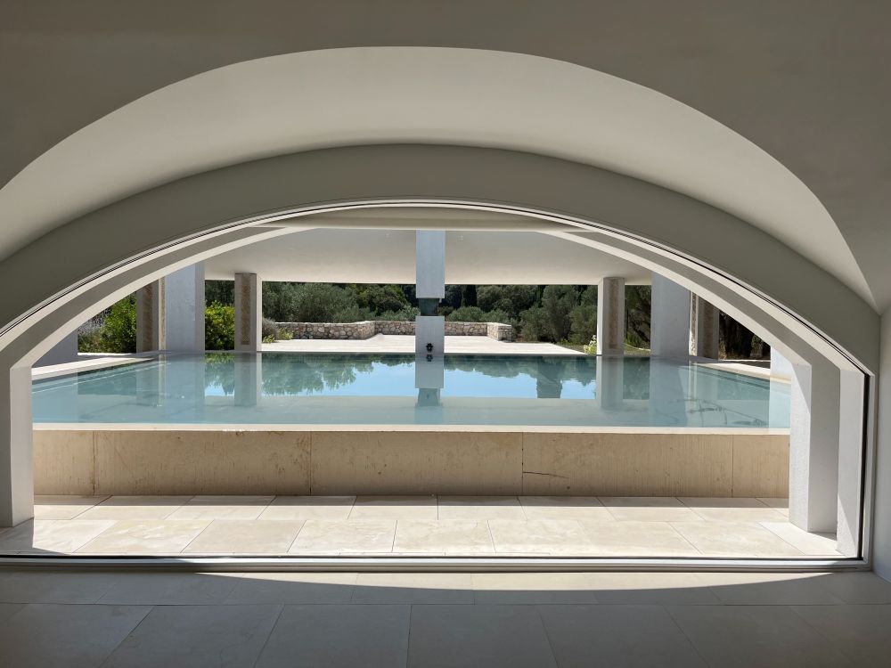 Vue d'une des fenêtres de la fondation, avec le plan d'eau au-dessus du toit en verre et une colonne avec une œuvre de Sosno.