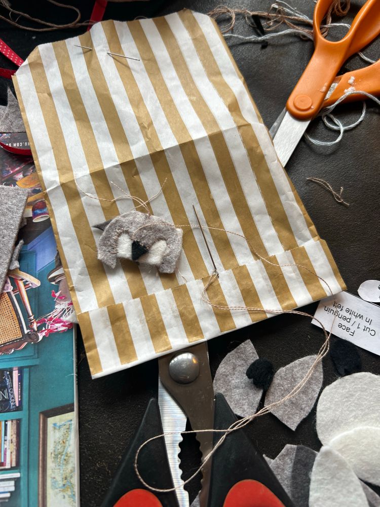 The very beginning of a felt penguin sewing project, with just her face sewn together 