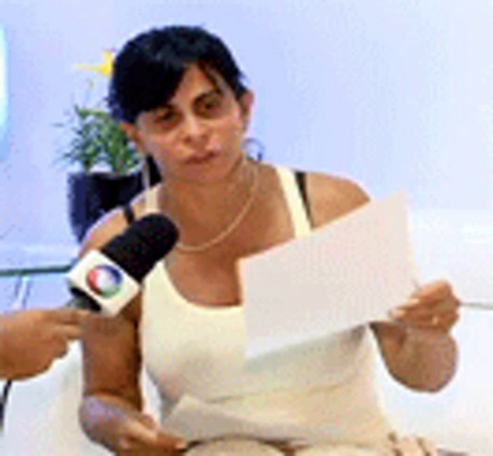 a woman is sitting on a couch holding a piece of paper and a microphone .