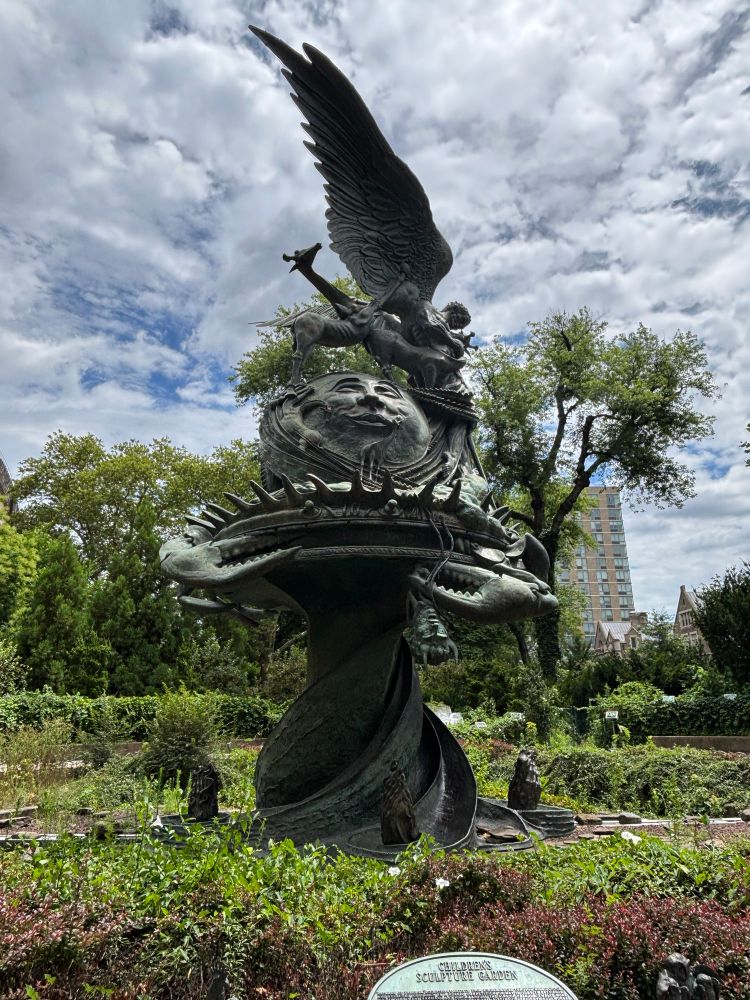 A large statue with a crab severing an upside down head, a giraffe thing, a moon face, wings, and a whole lot more 