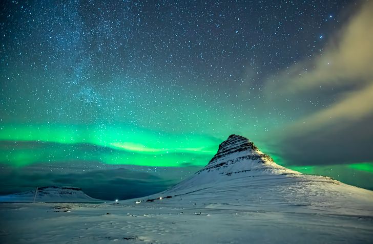 Photo of an aurora over snowy mountains at night. 