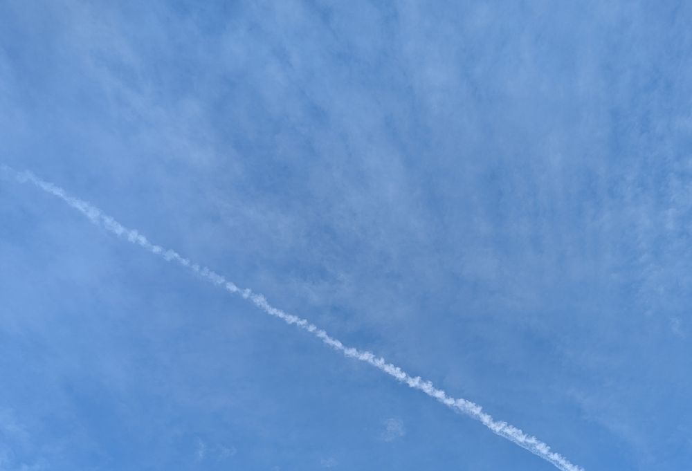 Bkauer Himmel mit zarten Wolken und Kondenzstreifen