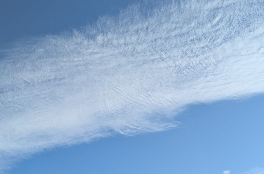 Blauer Himmel mit einer großen Schleierwolke, die quer durchs Bild geht. 