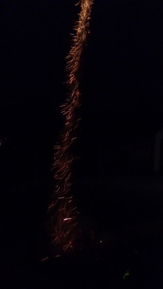Ein schmaler Streifen Funken zieht vertikal in die dunkle Nacht. 