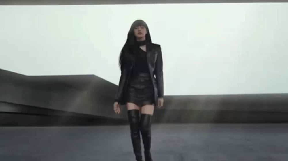 a woman in a black leather skirt and thigh high boots is standing in a room .