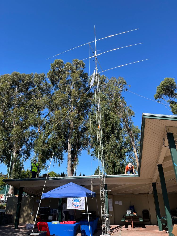 Circa 40 foot tall antenna with large Yagi and a vertical dipole on top leaving agains a park shelter.