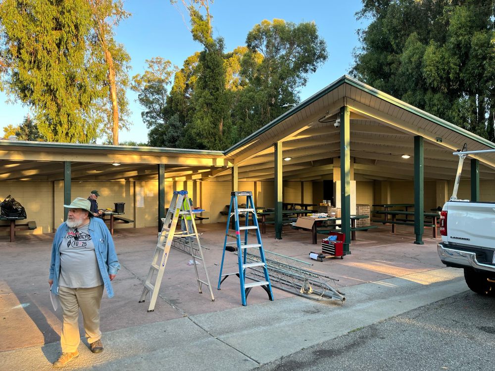 The shelter in Beresforf Park in San Mateo, CA. Two ladders, a few radio tower segments, and several tool chests are placed all over the area. 