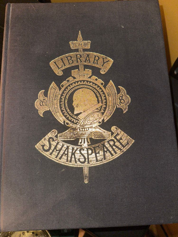 Photo of large brown leather book with gold foil embossed profile of William Shakespeare and the words “Library of Shakespeare” 