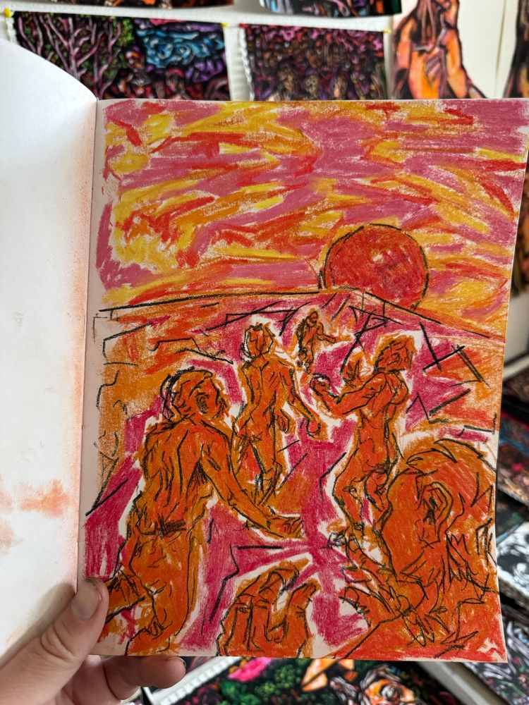 A hand holds a hardbound sketchbook open inside an artist’s studio - on the page is a sketch of figures running towards a horizon. Everything is shades of red. Art by Jason Thomas Pitzl. 