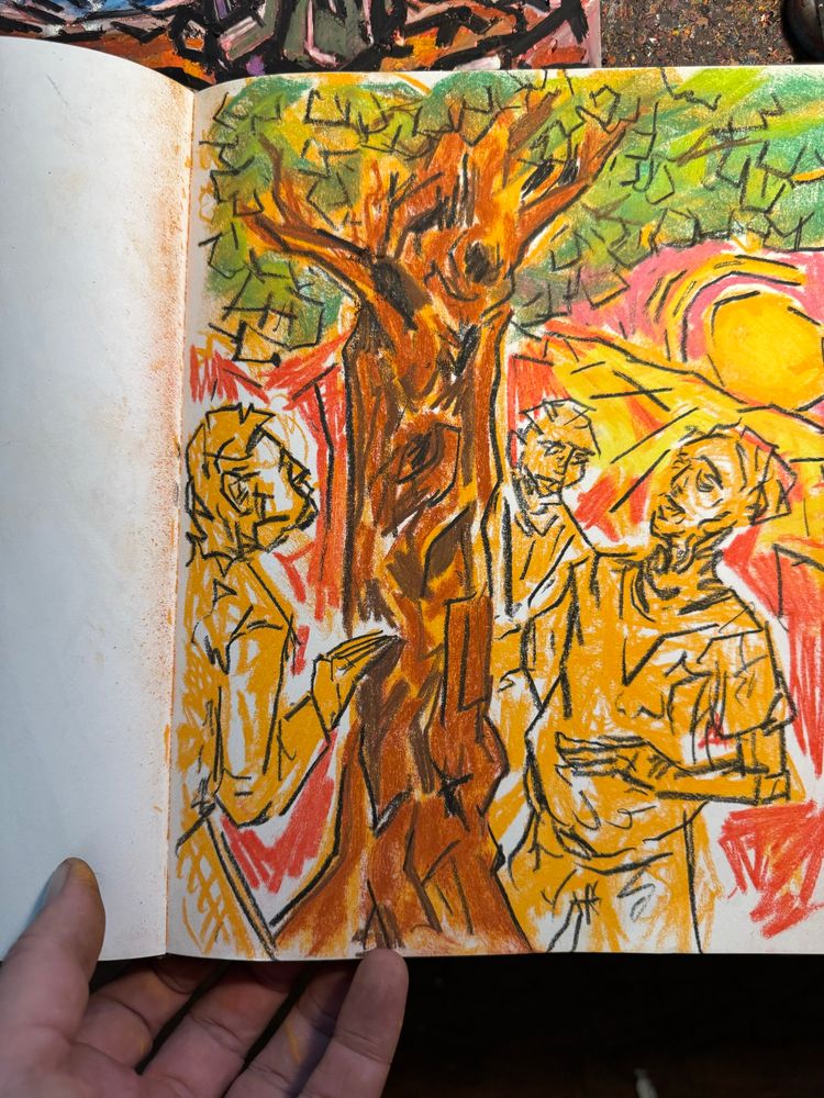A hand holds a hardbound sketchbook open on an artist’s table, inside is a conte crayon sketch of three figures standing around a tree. Art by Jason Thomas Pitzl. 