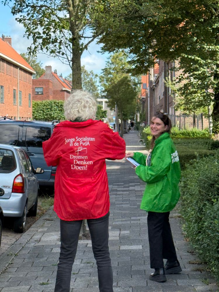 Twee campaigners met rode PvdA en groene GroenLinks-jasjes. 