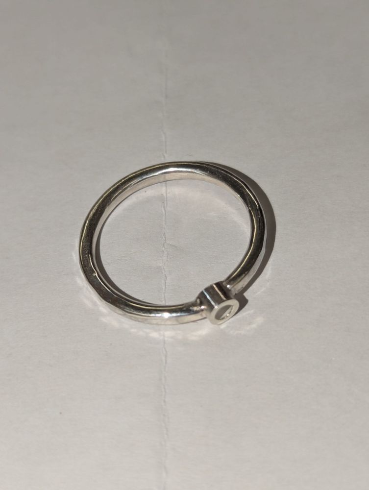 A silver ring with a small tube that has been soldered into the ring to serve as a setting for a small stone.
